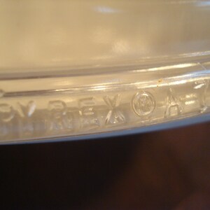 May include: Close-up of the bottom of a clear glass Pyrex baking dish with the words "PYREX" and a registered trademark symbol.