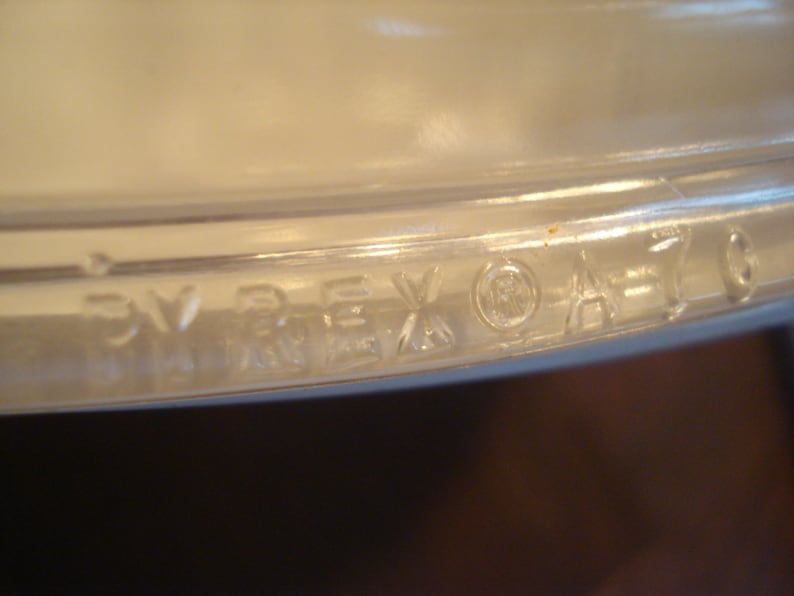 May include: Close-up of the bottom of a clear glass Pyrex baking dish with the words "PYREX" and a registered trademark symbol.