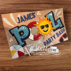 Op de afbeelding: Handgeschilderd bord met de woorden "JAMES' POOL PARTY BASH" in blauwe en witte letters. Een lachende zon met zonnebril, een rood-witte reddingsboei en een strandbal zijn ook afgebeeld. Het bord staat op een bruine achtergrond.