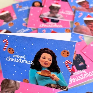 Può includere: Biglietti di auguri natalizi con varie immagini e le parole "buon natale". Le carte presentano immagini di persone, bastoncini di zucchero e biscotti. I colori di sfondo sono blu e rosa.