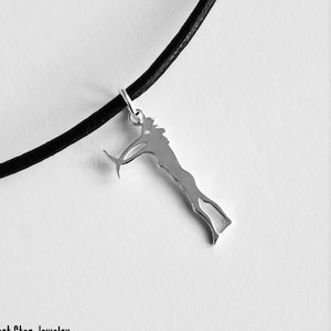 Può includere: Una collana d'argento con un ciondolo a forma di persona che tiene un pesce. La collana è su un cordoncino di cuoio nero.