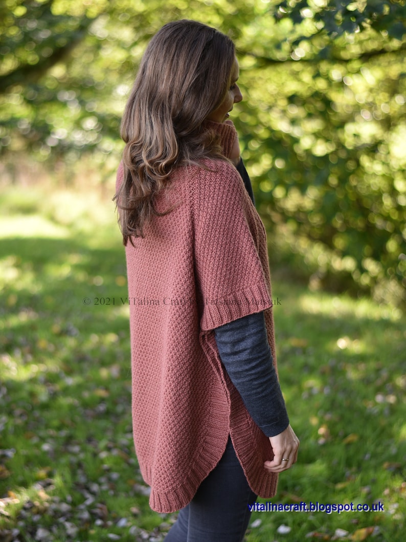 K&ouml;nnte beinhalten: Eine Frau tr&auml;gt einen rostigen Strickponcho mit hohem Kragen und gerippter Struktur. Der Poncho hat eine leicht ausgestellte Form und wird &uuml;ber einem schwarzen Langarmshirt und einer schwarzen Hose getragen.