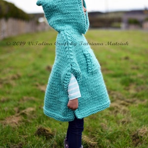 May include: A turquoise knitted hooded poncho with a white striped long-sleeve shirt underneath. The poncho is worn by a child standing in a grassy field. &copy; 2019 Vitalina Craft by Tatsiana Matsiuk vitalinacraft.blogspot.co.uk