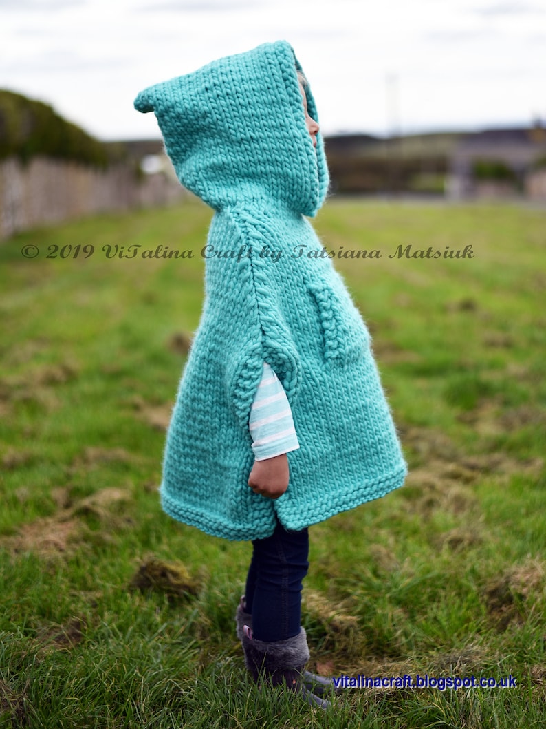 May include: A turquoise knitted hooded poncho with a white striped long-sleeve shirt underneath. The poncho is worn by a child standing in a grassy field. &copy; 2019 Vitalina Craft by Tatsiana Matsiuk vitalinacraft.blogspot.co.uk