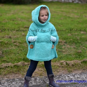 May include: A turquoise knitted hooded poncho with a pocket and wooden buttons. The poncho is worn by a child standing on a path.