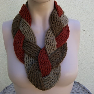 May include: A braided knit scarf in brown and red colors. The scarf is made of a soft, chunky yarn and is perfect for keeping warm in the winter.