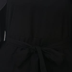 May include: A close-up of a black dress with a tied waist. The dress is made of a smooth fabric and features a bow detail at the waist. The dress appears to be a solid color, with no visible patterns or embellishments.