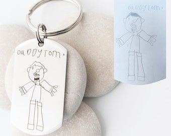 May include: Silver keychain with a personalized drawing of a person with the text "daddy tom." on it.