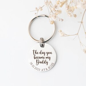 30mm stainless steel engraved keyring. Text reads The day you became my Daddy and is customisable with a child's name and date of birth around the bottom curve of the disc.