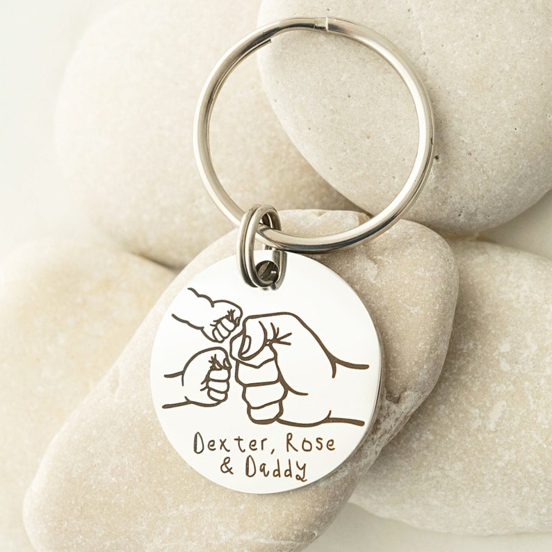 May include: Silver keychain with a round tag featuring three fist bumps and the text "Dexter, Rose & Daddy".