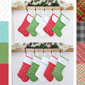 May include: Six red, green, and white Christmas stockings with snowflake patterns hang from a wooden shelf with a garland of greenery.