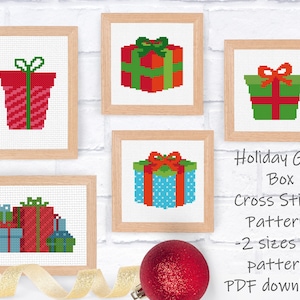 Op de afbeelding: Vijf kruissteekpatronen met verschillende ontwerpen van cadeaudozen met strikken. De patronen zijn ingelijst in hout en worden weergegeven op een witte bakstenen muur. De tekst "Holiday Gift Box Cross Stitch Patterns -2 sizes per pattern- PDF downloads" wordt onder de patronen weergegeven.