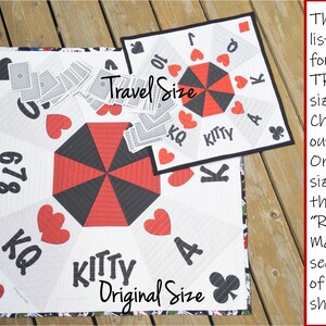 May include: Two quilted game mats, one labeled "Travel Size" and the other "Original Size". Both mats feature a black and red umbrella design with playing card symbols and numbers. The mats are made of white fabric with black and red quilting.