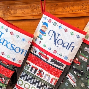 May include: Three Christmas stockings with personalized names, Jaxson, Noah, and a snowman design. The stockings are decorated with red, green, and white fabric.