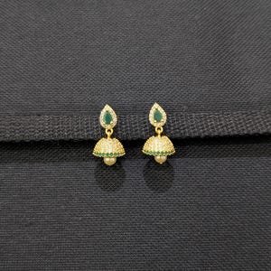Könnte beinhalten: Ein Paar goldfarbene Ohrringe mit einem tropfenförmigen grünen Stein und einem glockenförmigen Boden. Der glockenförmige Boden ist mit kleinen, klaren Steinen und einer kleinen Perle besetzt. Auf dunklem Hintergrund präsentiert.