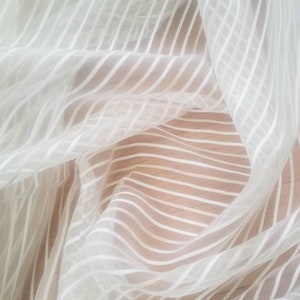 Sheer drapery fabric 110 inches wide striped design.  Off white base with beige and creme stripes usable for interior designing.