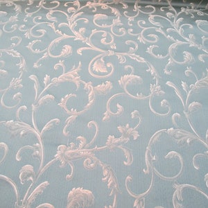 May include: A light blue fabric with a white damask pattern of swirling vines and leaves.