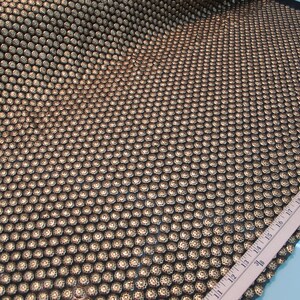 May include: Black fabric with a repeating pattern of gold-colored circles. A ruler is visible in the bottom right corner of the image.