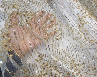 May include: White mesh fabric with gold and silver sequins and beads. The fabric has a vertical striped pattern.