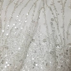 Hand beaded elegantly Beading  This gorgeous sheer dress Fabric creating a very detailed design. White base with silver beading.