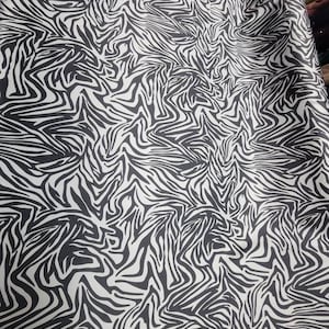 May include: Black and white zebra print fabric with a wavy pattern.
