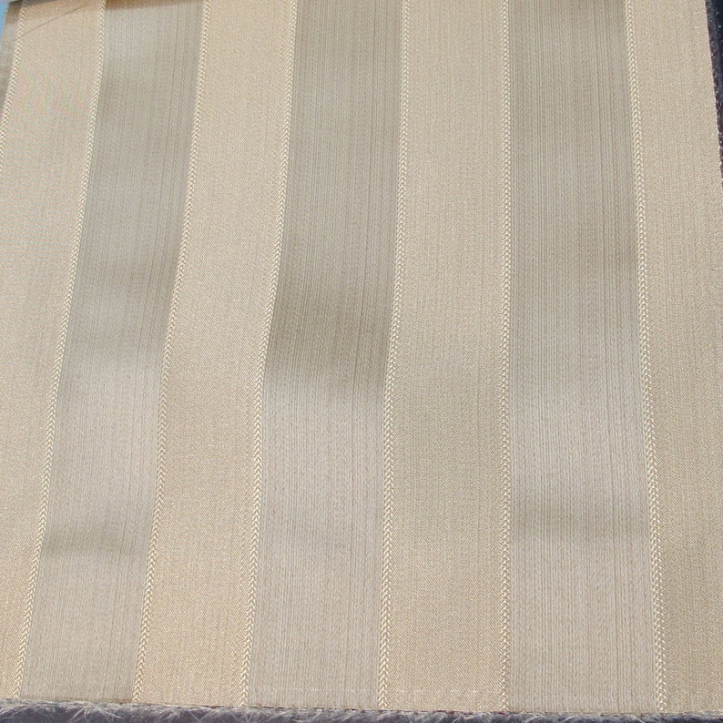 May include: Beige fabric with vertical stripes of a slightly darker beige color.
