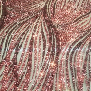 May include: Red and rose gold sequined fabric with a wavy pattern. The sequins are arranged in vertical lines.