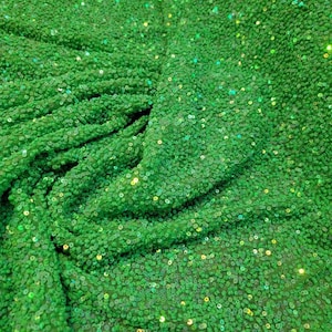 May include: Green fabric with small, iridescent sequins. The sequins are densely packed and create a shimmering effect.