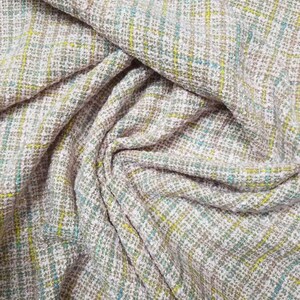 May include: Close-up of a textured fabric with a pink, white, yellow, and blue plaid pattern.