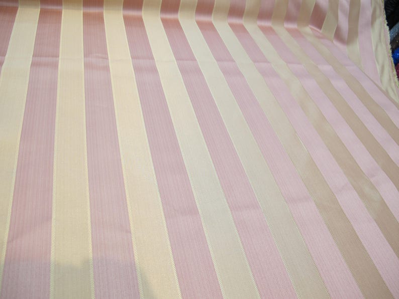 May include: A fabric with alternating stripes of light pink and cream.