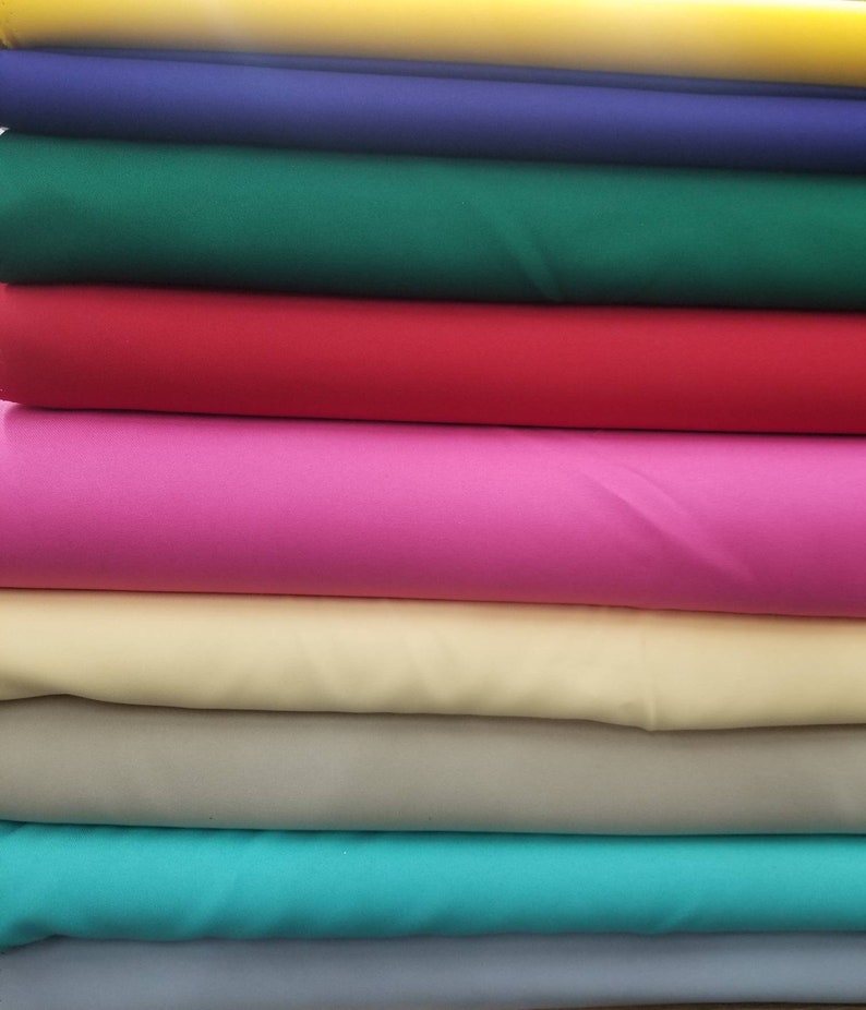 K&ouml;nnte beinhalten: Stapel von Stoffproben in verschiedenen Farben, darunter Gelb, Blau, Gr&uuml;n, Rot, Rosa, Beige, T&uuml;rkis und Grau.