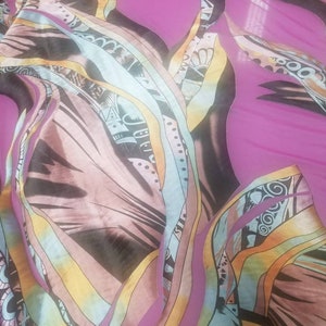 Pode incluir: Tecido abstrato com fundo rosa e um padr&atilde;o colorido e espiralado. O tecido tem um visual em camadas com diferentes tons de azul, amarelo e marrom.