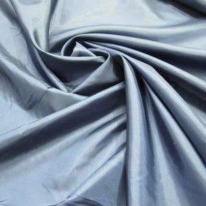 May include: A close-up of a smooth, dark blue fabric with a silky sheen. The fabric is folded and draped, showcasing its texture and drape.