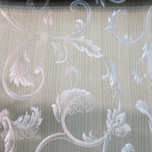 May include: Close-up of a beige fabric with a silver floral pattern. The fabric has a subtle texture and a woven look.