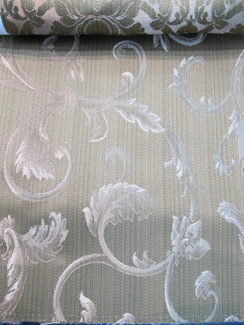 May include: Close-up of a beige fabric with a silver floral pattern. The fabric has a subtle texture and a woven look.