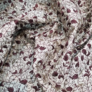 Beige color shantung fabric beautifully thread embroidered with a dark brownish maroon color that takes its elegant look. 45&quot; Wide fabric.