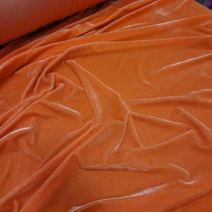 Orange color Stretch velvet is 4 way stretch,  polyester fabric with a beautiful sheen usable for apparel,  accessories,  interiors