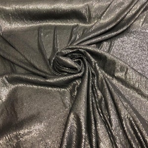 Może przedstawiać: Czarny materiał z srebrnymi cekinami. Materiał jest udrapowany i złożony, aby pokazać fakturę cekinów.