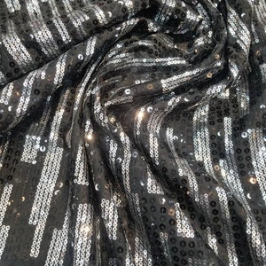 Puede incluir: Tela negra con lentejuelas plateadas dispuestas en rayas verticales.