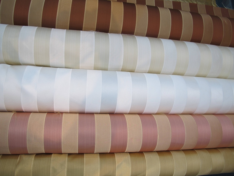 May include: Four rolls of striped fabric in different colors, including brown, beige, white, and pink.