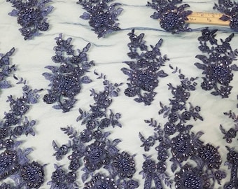 May include: Navy blue beaded lace fabric with a floral design. The lace is delicate and intricate, with small beads scattered throughout. The fabric is perfect for adding a touch of elegance to any project.
