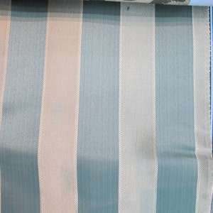 May include: A close-up of a fabric with alternating stripes of light blue and beige. The stripes have a subtle herringbone pattern.
