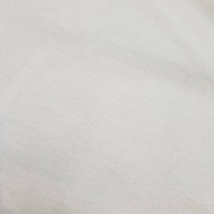 Puede incluir: Una superficie de tela blanca lisa con una textura sutil.