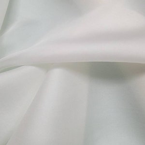 Peut inclure: Tissu blanc avec une texture lisse et soyeuse. Le tissu est plié en deux, créant un drapé doux et fluide.