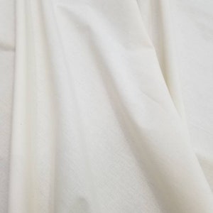 Puede incluir: Primer plano de una tela blanca con una textura suave. La tela est&aacute; doblada y drapeada, mostrando su naturaleza suave y fluida.