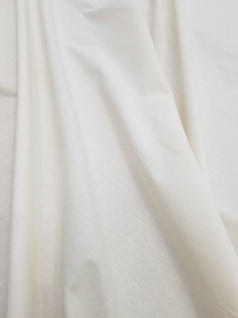 Puede incluir: Primer plano de una tela blanca con una textura suave. La tela est&aacute; doblada y drapeada, mostrando su naturaleza suave y fluida.