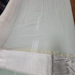 Off white silk chiffon  with two side off white and gold stripe borders usable for apparel and accessories.