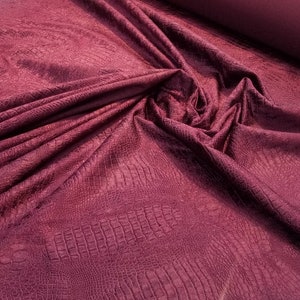 Może przedstawiać: Burgundowy materiał imitujący sk&oacute;rę krokodyla z fakturowanym, lekko błyszczącym wykończeniem.
