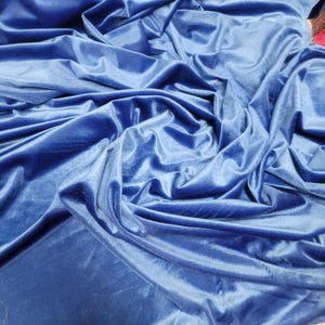 May include: A close-up of a blue velvet fabric, showing the soft texture and drape of the material.