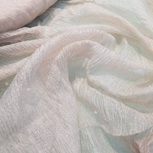 Metaliczna, biała, krinikledowa jedwabna organza. 100% jedwabna organza. Nadaje się do odzieży i projektowania wnętrz.
